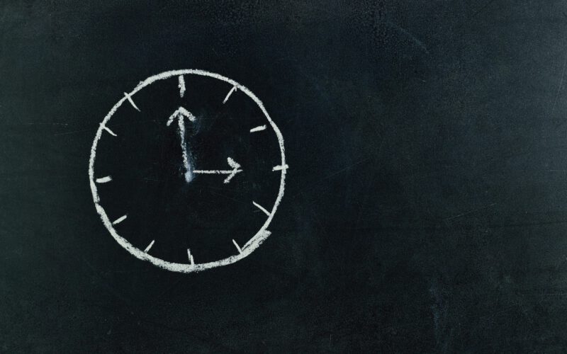 Chalk-drawn clock on a blackboard, symbolizing time and education concepts.